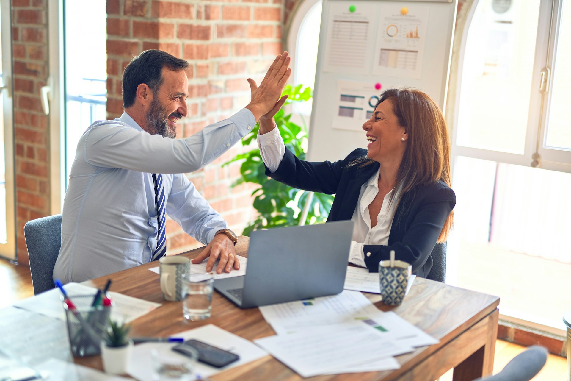 man and women high fiving at a desk